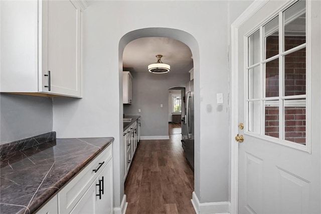 159 Jefferson Ave, Vandergrift Wml, PA 15690 - kitchen with arched walkways, dark countertops, dark wood-style flooring, white cabinetry, and baseboards