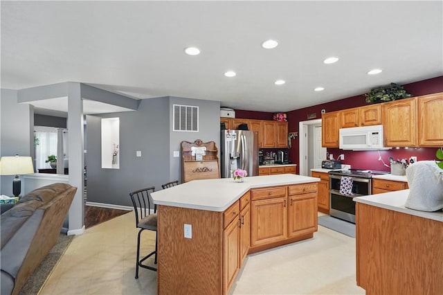 923 Arberdeen Dr, Hempfield Twp Wml, PA 15601 - kitchen featuring appliances with stainless steel finishes, a kitchen island, light countertops, recessed lighting, and a kitchen bar