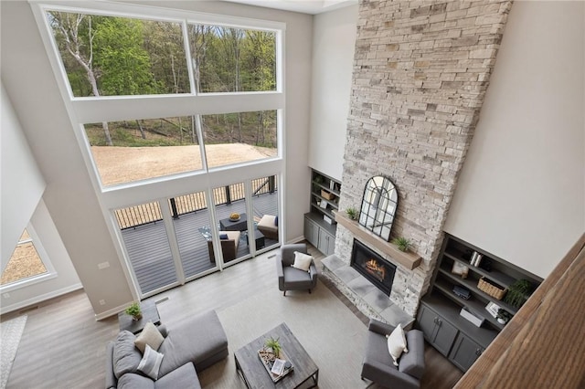9660 Goehring Rd, Cranberry Twp, PA 16066 - living room featuring a towering ceiling, wood finished floors, a stone fireplace, and baseboards