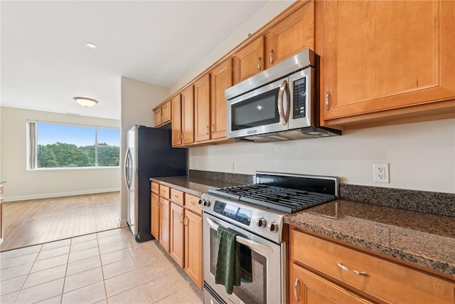 5570 Centre Ave Unit 306, Shadyside, PA 15232 - kitchen featuring appliances with stainless steel finishes, brown cabinetry, dark stone countertops, and light tile patterned floors