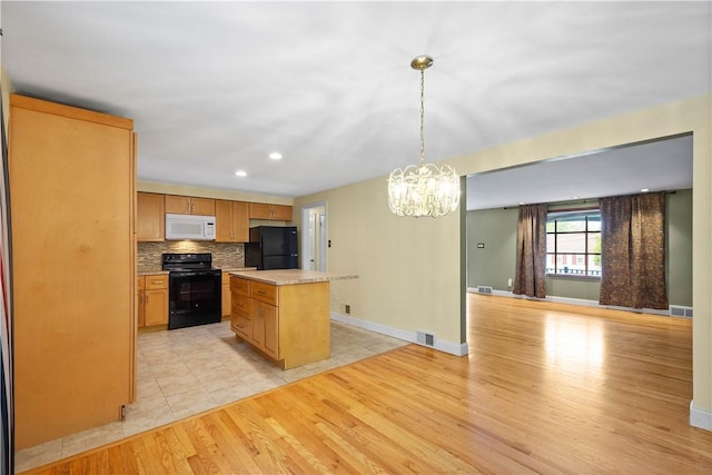 1064 Glen Oak Dr, Bethel Park, PA 15102 - kitchen with black appliances, a center island, a chandelier, light countertops, and light wood-style flooring