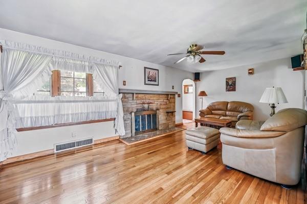 260 S Oakdale Ave, Hermitage, PA 16148 - living room featuring ceiling fan, wood finished floors, a stone fireplace, and arched walkways