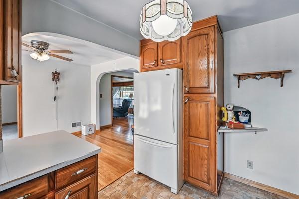 260 S Oakdale Ave, Hermitage, PA 16148 - kitchen with freestanding refrigerator, arched walkways, a ceiling fan, and brown cabinetry