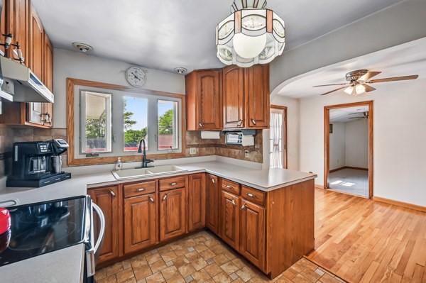 260 S Oakdale Ave, Hermitage, PA 16148 - kitchen with stainless steel range with electric stovetop, a sink, a peninsula, under cabinet range hood, and healthy amount of natural light
