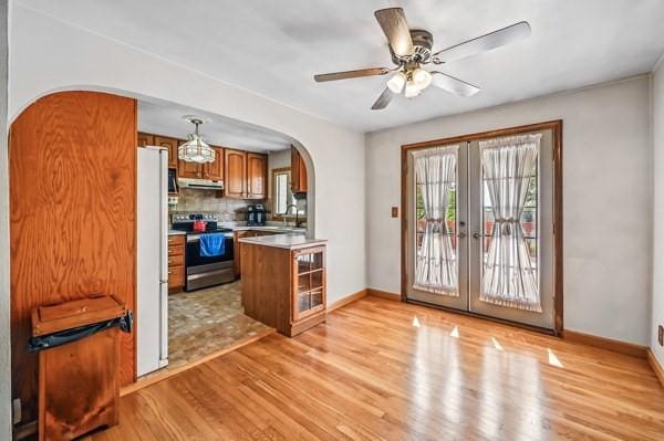 260 S Oakdale Ave, Hermitage, PA 16148 - kitchen featuring electric stove, under cabinet range hood, arched walkways, brown cabinets, and light wood-style flooring