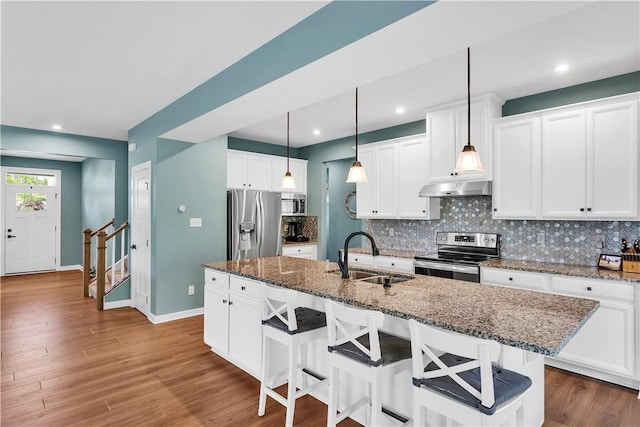 121 Derby Ln, North Fayette, PA 15071 - kitchen with appliances with stainless steel finishes, a sink, under cabinet range hood, decorative backsplash, and a kitchen bar