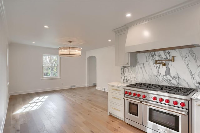 129 S Dr, Fox Chapel, PA 15238 - kitchen with range with two ovens, arched walkways, custom exhaust hood, tasteful backsplash, and recessed lighting