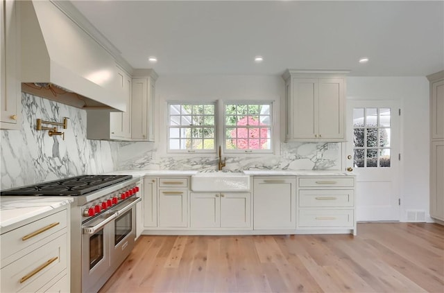 129 S Dr, Fox Chapel, PA 15238 - kitchen with a sink, double oven range, light wood-style floors, custom exhaust hood, and backsplash