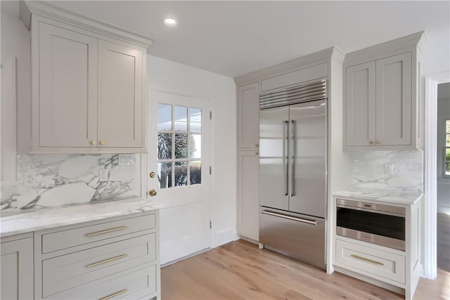 129 S Dr, Fox Chapel, PA 15238 - kitchen with built in refrigerator, backsplash, light wood-style floors, healthy amount of natural light, and recessed lighting