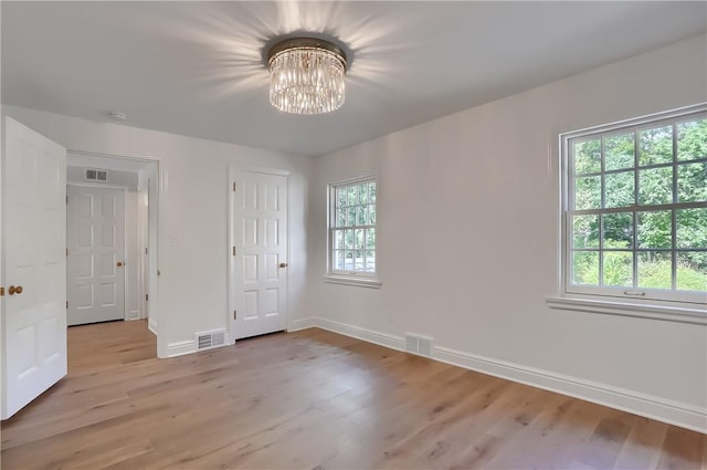 129 S Dr, Fox Chapel, PA 15238 - unfurnished bedroom featuring multiple windows, a chandelier, light wood-type flooring, and baseboards