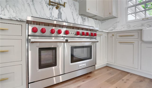 129 S Dr, Fox Chapel, PA 15238 - kitchen view of double oven range, decorative backsplash, pot filler, light wood-style flooring, and light countertops