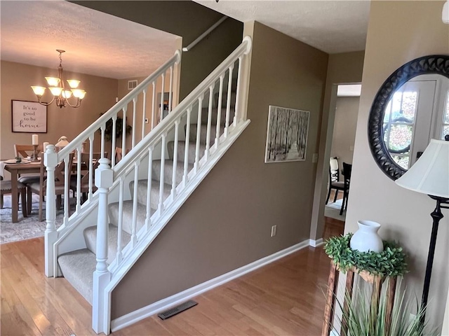 138 Willow Run Dr, Center Twp But, PA 16001 - staircase featuring wood finished floors, a chandelier, and baseboards