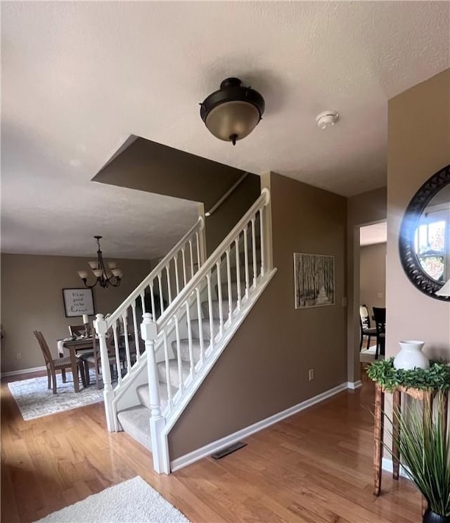 138 Willow Run Dr, Center Twp But, PA 16001 - staircase featuring wood finished floors, baseboards, and a chandelier