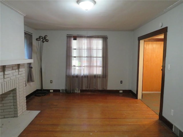 1111 Progress St, Mckees Rocks, PA 15136 - unfurnished living room with wood finished floors, a brick fireplace, crown molding, and baseboards