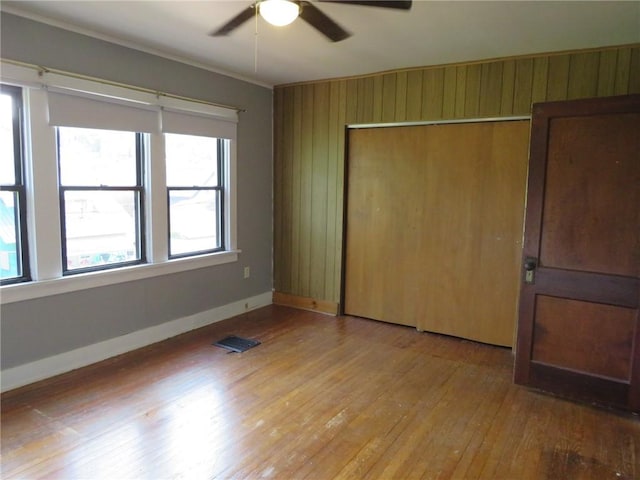 1111 Progress St, Mckees Rocks, PA 15136 - unfurnished bedroom featuring hardwood / wood-style floors, baseboards, wooden walls, a closet, and ornamental molding
