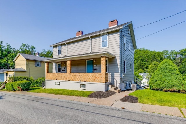 149-151 French St, Hempfield Twp Wml, PA 15601 - view of front facade featuring a chimney, brick siding, central AC unit, a porch, and a front lawn