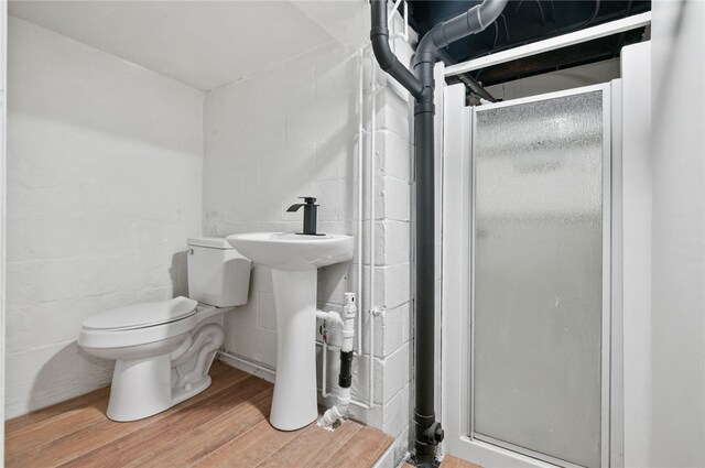 3702 School Rd, Murrysville, PA 15668 - bathroom with a stall shower, toilet, concrete block wall, wood finished floors, and a sink