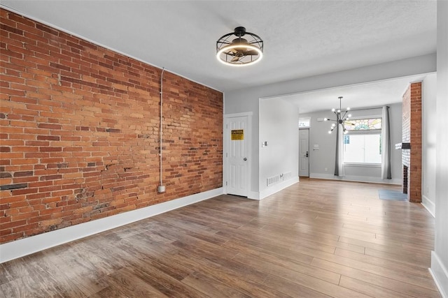 2532 Larkins Way S, Side, PA 15203 - spare room featuring brick wall, a chandelier, baseboards, and wood finished floors
