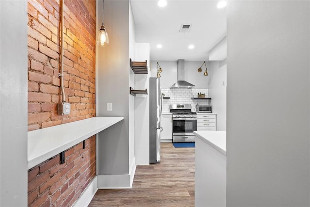 2532 Larkins Way S, Side, PA 15203 - kitchen with appliances with stainless steel finishes, wall chimney range hood, light wood-type flooring, decorative backsplash, and brick wall