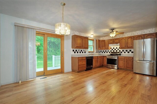 317 Fairview Dr, Manor, PA 15642 - kitchen featuring stainless steel appliances, under cabinet range hood, brown cabinetry, light countertops, and decorative backsplash