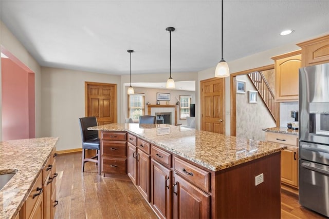 1616 Norman Dr, Franklin Park, PA 15143 - kitchen with stainless steel fridge, a center island, dark wood finished floors, a fireplace, and light stone counters