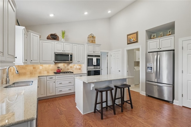 112 Savannah Dr, Lancaster Twp, PA 16037 - kitchen with appliances with stainless steel finishes, a sink, backsplash, wood finished floors, and a kitchen breakfast bar