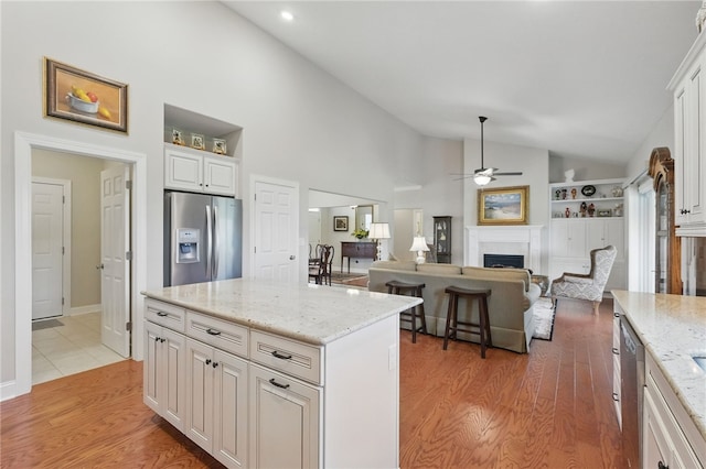112 Savannah Dr, Lancaster Twp, PA 16037 - kitchen with stainless steel fridge, vaulted ceiling, a ceiling fan, a fireplace, and light wood-style flooring