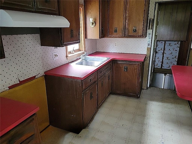 214 Washington Ave, Mount Pleasant Twp Was, PA 15340 - kitchen with wallpapered walls, under cabinet range hood, light floors, a sink, and dark brown cabinetry