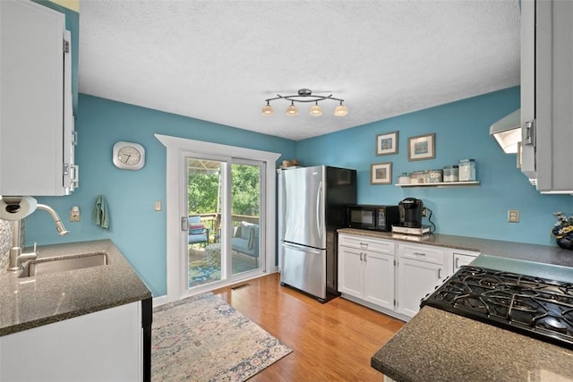 208 Ruffed Grouse Dr, North Fayette, PA 15126 - kitchen with freestanding refrigerator, black microwave, a sink, white cabinets, and wall chimney range hood