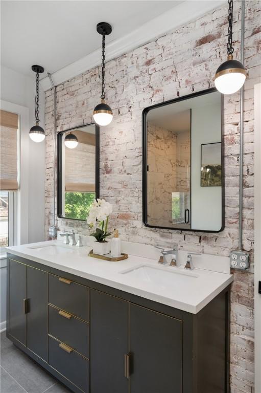 323 44th St, Lawrenceville, PA 15201 - full bath with double vanity, plenty of natural light, brick wall, and tile patterned floors