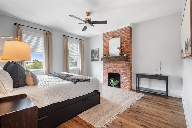 323 44th St, Lawrenceville, PA 15201 - bedroom with wood finished floors, a brick fireplace, a ceiling fan, and baseboards