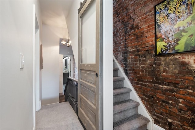 323 44th St, Lawrenceville, PA 15201 - stairway with baseboards, brick wall, a chandelier, and carpet