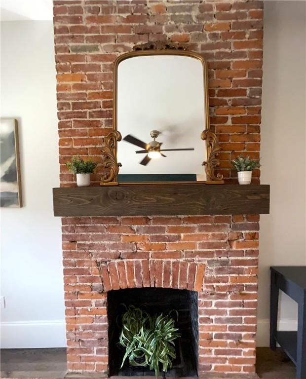 323 44th St, Lawrenceville, PA 15201 - detailed view of a brick fireplace, a ceiling fan, baseboards, and wood finished floors
