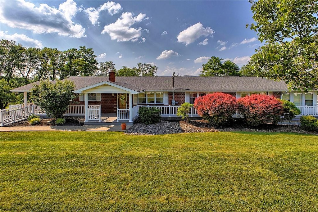 2173 State Route 119, Hempfield Twp Wml, PA 15601 - view of front of property with covered porch, a chimney, brick siding, and a front yard