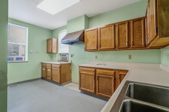 1632 Lincoln Way, White Oak, PA 15131 - kitchen featuring wall chimney exhaust hood, brown cabinetry, light countertops, and baseboards