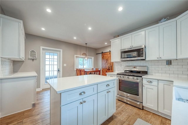 429 Market St, Beaver, PA 15009 - kitchen with stainless steel appliances, a kitchen island, white cabinetry, light wood-style floors, and decorative backsplash