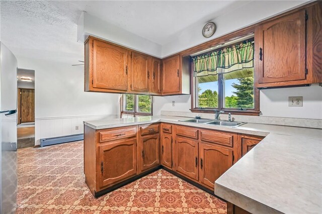 1011 S Lake Rd, Jefferson Twp Mer, PA 16137 - kitchen featuring a sink, a baseboard radiator, light countertops, a peninsula, and brown cabinets