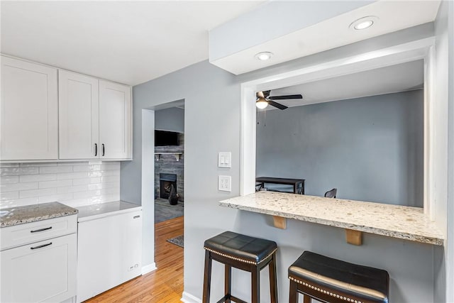 2693 Crosby Ave, Dormont, PA 15216 - kitchen with a kitchen breakfast bar, white cabinets, light wood-style flooring, backsplash, and ceiling fan