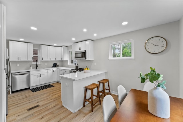 1416 Swantek St, Sheraden, PA 15204 - kitchen featuring stainless steel appliances, a peninsula, a sink, a breakfast bar area, and light wood-style flooring