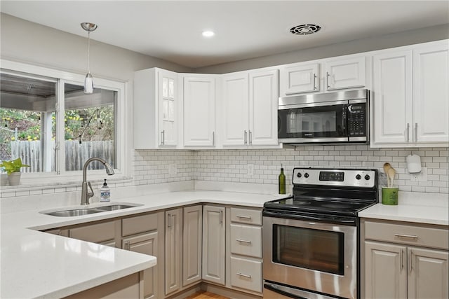 1450 Mohican Dr, Mt Lebanon, PA 15228 - kitchen with appliances with stainless steel finishes, a sink, tasteful backsplash, light countertops, and hanging light fixtures