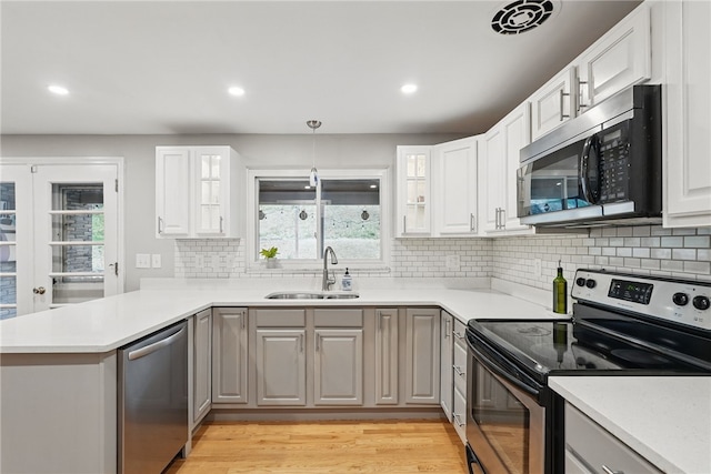 1450 Mohican Dr, Mt Lebanon, PA 15228 - kitchen with stainless steel appliances, a sink, a peninsula, backsplash, and light wood-style floors
