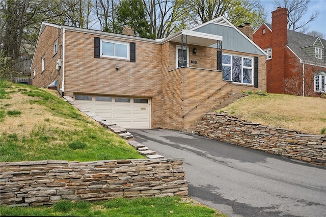 1450 Mohican Dr, Mt Lebanon, PA 15228 - view of front of property with driveway, an attached garage, a chimney, brick siding, and a front lawn