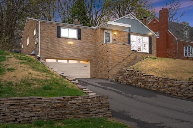 1450 Mohican Dr, Mt Lebanon, PA 15228 - view of front facade with a garage, driveway, a chimney, brick siding, and a front lawn