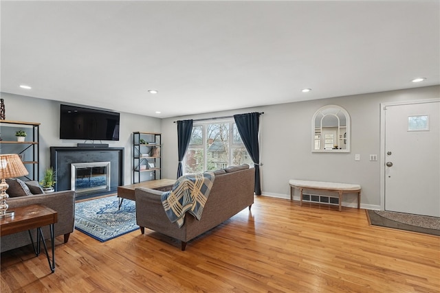 1450 Mohican Dr, Mt Lebanon, PA 15228 - living area with light wood-type flooring, a glass covered fireplace, recessed lighting, and baseboards