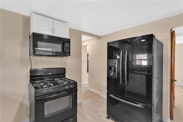 427 Cedar St, Jeannette, PA 15644 - kitchen featuring black appliances, white cabinets, light wood-type flooring, and baseboards
