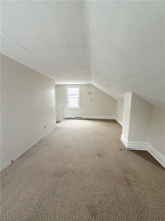 610 Southern Ave, Mt Washington, PA 15211 - additional living space with a textured ceiling, light colored carpet, and lofted ceiling
