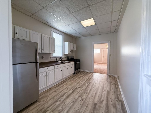610 Southern Ave, Mt Washington, PA 15211 - kitchen with stainless steel appliances, dark countertops, a sink, light wood finished floors, and a paneled ceiling