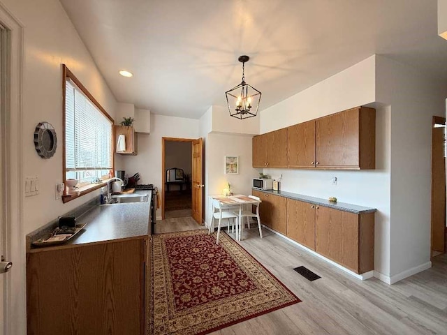 610 Southern Ave, Mt Washington, PA 15211 - kitchen featuring a sink, light wood-style floors, a chandelier, brown cabinetry, and decorative light fixtures