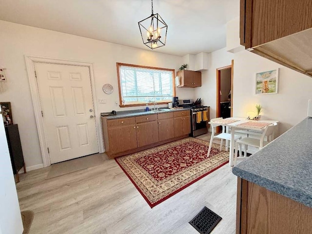 610 Southern Ave, Mt Washington, PA 15211 - kitchen with stainless steel range with gas cooktop, light wood-type flooring, a sink, brown cabinetry, and a chandelier
