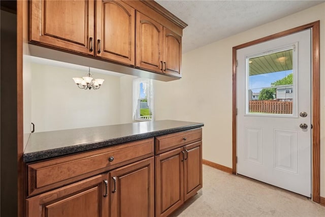 211 Old Meadow Dr, Hempfield Twp Wml, PA 15601 - kitchen featuring brown cabinets, dark countertops, baseboards, a chandelier, and light floors